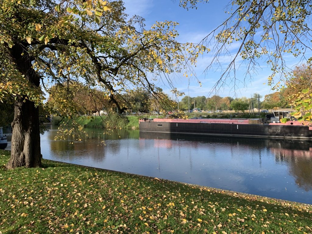 La péniche du Bus Magique vue depuis la berge de la Deûle, sous les arbres