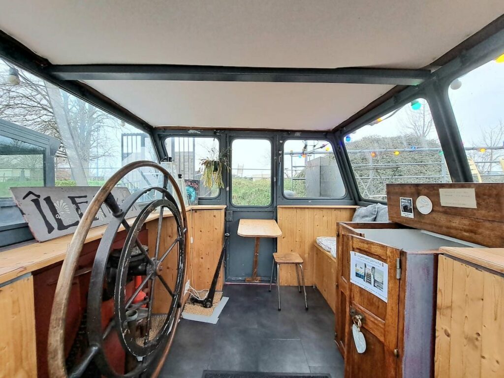Timonerie de la péniche avec sa barre à roue d'origine et sa vue sur le canal